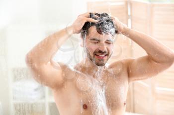Handsome man washing hair at home�