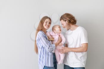Happy parents with cute little baby on light background�
