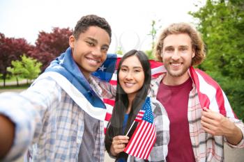 Group of students with USA flag taking selfie outdoors�
