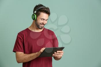 Young man listening to audiobook on color background�