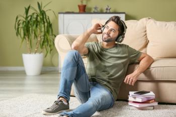 Young man listening to audiobook at home�