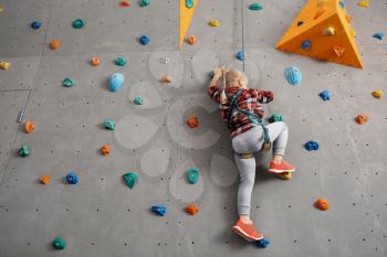 Little girl climbing wall in gym�