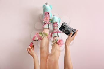Woman in vintage roller skates, with flowers and photo camera on light background�