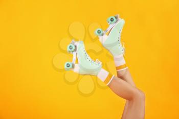 Legs of woman in roller skates on color background�