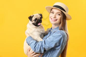 Beautiful young woman with cute pug dog on color background�