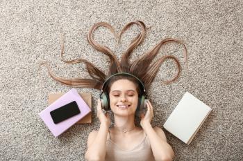 Beautiful young woman listening to audiobook at home�
