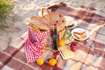 Wicker basket with tasty food and drink for romantic picnic on beach�