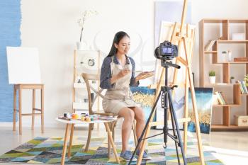 Female Asian blogger recording video in workshop�
