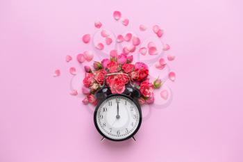 Beautiful fresh flowers and clock on color background�