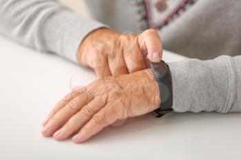Elderly woman with fitness band checking her pulse, closeup�