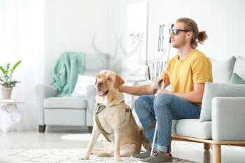 Blind young man with guide dog at home�