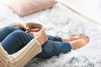 Young woman drinking hot tea at home�