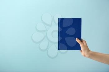Female hand with book on color background�