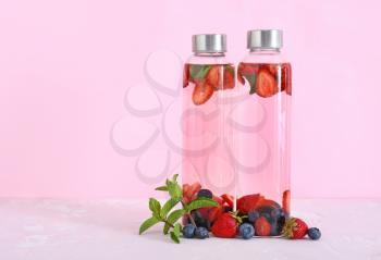 Bottles of tasty infused water on color background�