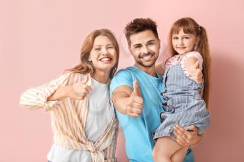 Portrait of happy family showing thumb-up gesture on color background�