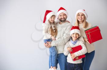 Happy family with Christmas gifts on light background�