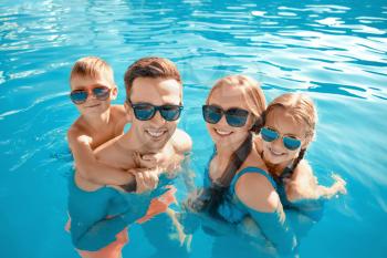Happy family in swimming pool on summer day�