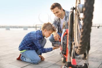 Father and his son repairing bicycle outdoors�