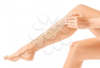 Beautiful young woman applying body scrub against white background�