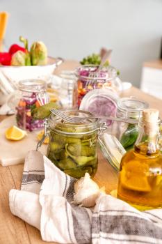 Jar with canned cucumbers on wooden table in kitchen�