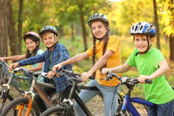 Cute children riding bicycles outdoors�