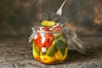 Jar with different canned vegetables on grunge background�