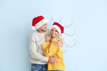 Happy couple in Santa hats on color background�