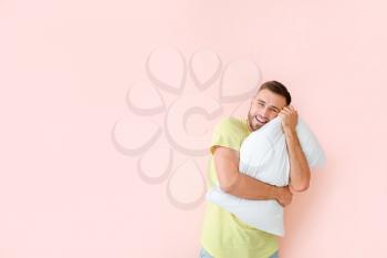 Young man with pillow on color background�