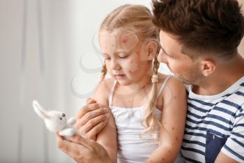 Man taking care of his little daughter ill with chickenpox at home�