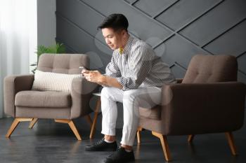 Asian man with mobile phone at home�