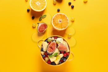 Pot with tasty fruit salad on color background�