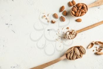 Spoons with tasty almonds on white background�