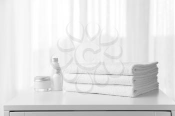 Soft clean towels and cosmetics on table near window�