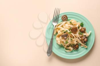Plate with tasty cooked mushrooms and pasta on color background�