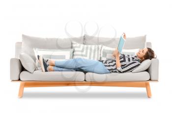Young woman reading book while lying on sofa against white background�