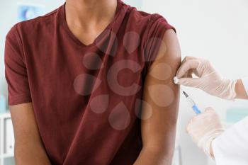 Doctor vaccinating teenage boy in clinic, closeup�