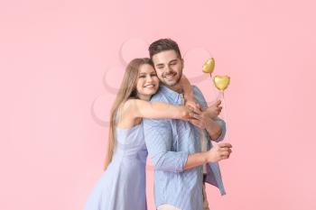 Happy young couple with hearts on color background�