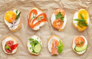 Sandwiches with tasty cream cheese on parchment�