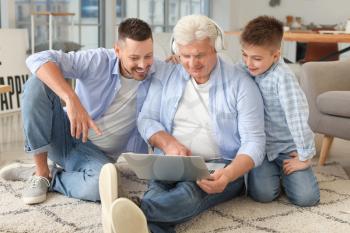 Man with his father and son using laptop at home�