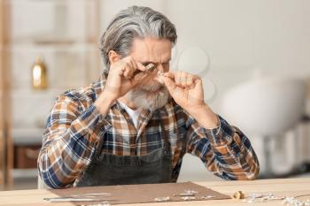 Jeweler examining adornment in workshop�