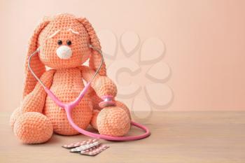 Stethoscope, pills and baby toy on table�