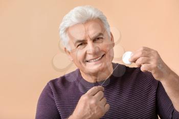 Senior man flossing teeth on color background�
