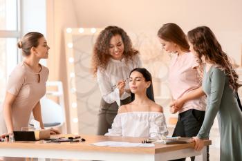 Young woman teaching students in makeup school�