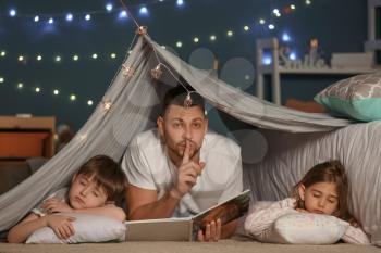 Father with book and his little sleeping children at home�