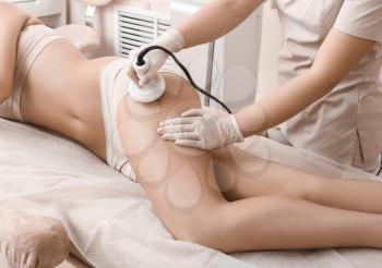 Beautiful woman undergoing procedure of anti-cellulite massage in beauty salon�