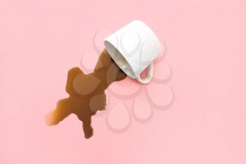 Overturned cup of coffee on color background�