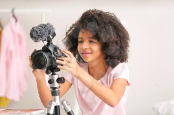 African-American teenage blogger adjusting camera for recording video at home�