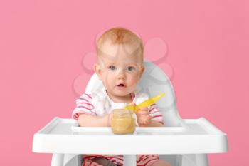 Little baby eating food against color background�