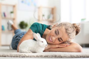 Beautiful young woman with cute rabbit at home�