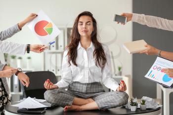 Businesswoman with a lot of work to do meditating in office�